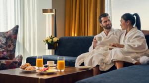 Couple sitting on the sofa in front of a coffee table with room service laid out