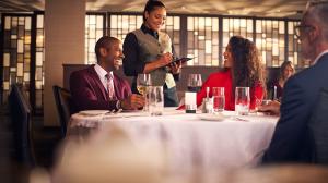 A group of people at a fine dining resturant with a smiling waitress taking their order